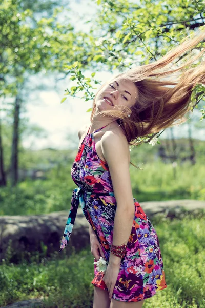 Portrait of beautiful blond young woman having fun playing with long hair & looking at camera on green summer copy space outdoors background Stock Picture
