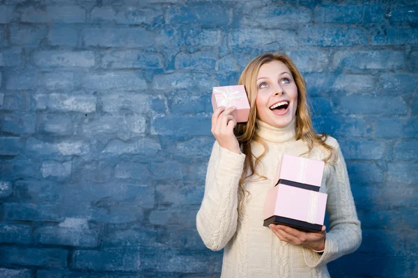 Attrayant blond jeune femme en chandail de laine recevoir des cadeaux ayant plaisir heureux sourire sur fond de mur de brique bleue — Photo