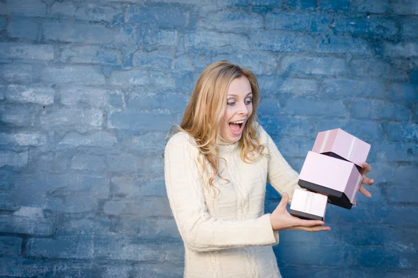 Attrayant blond jeune femme en chandail de laine recevoir des cadeaux ayant plaisir heureux sourire sur fond de mur de brique bleue — Photo