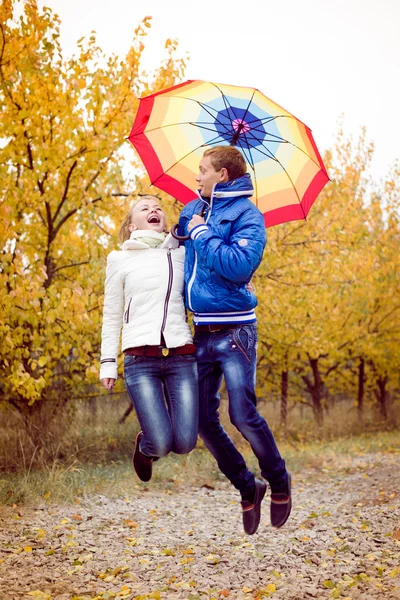 Happy teen couple jumping outdoors on cold autumn day — Stock Photo, Image