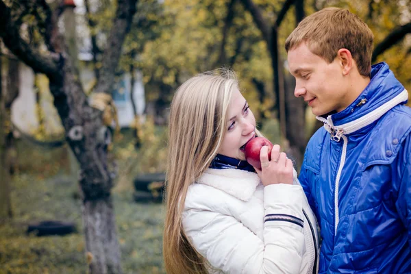 Happy teen couple outdoors on cold autumn day sharing apple — Stock Photo, Image