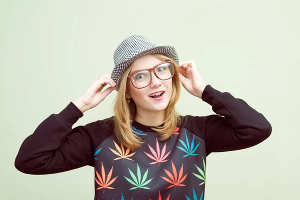 Studio portrait of teenage hipster girl wearing trendy eyeglasses and hat over olive copy space background — Stock Photo, Image