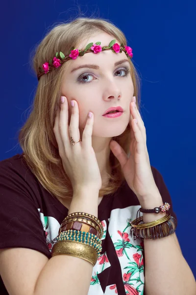 Retrato de estudio de hipster adolescente o chica hippie que lleva una corona de flores de moda sobre fondo de espacio de copia azul —  Fotos de Stock