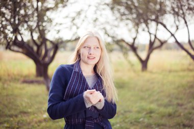 Güz parkında poz veren yün paltolu güzel bir genç kadın.