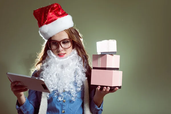 Chica en sombrero de Navidad, gafas y barba santa celebración de una Navidad bolas y regalos —  Fotos de Stock