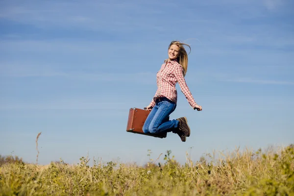 Ragazza che salta con valigia retrò — Foto Stock