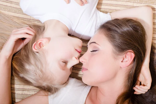 Mother and daughter lying on sofa