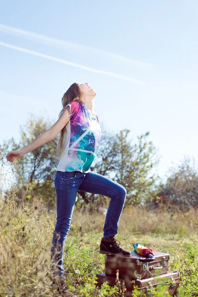 Girl with retro suitcases in field — Stock Photo, Image