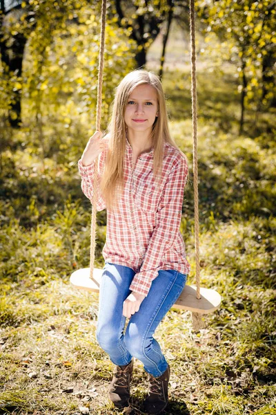 Dziewczyna siedzi na swing — Zdjęcie stockowe