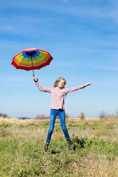 Teenage girl jumping with colorful umbrella — Stock Photo, Image