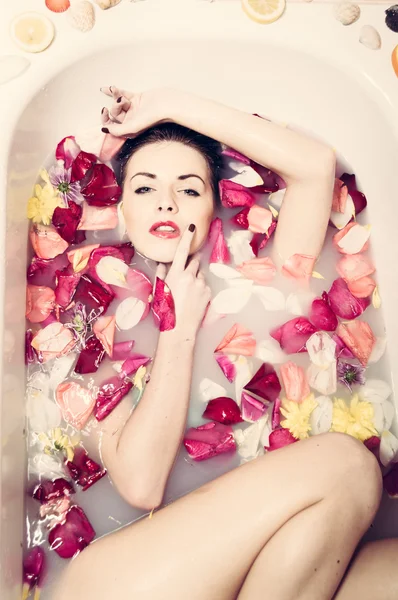 Woman in bath with flowers petals — Stock Photo, Image