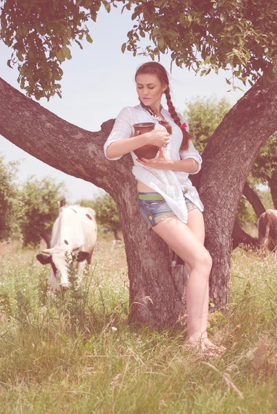 Jovem agricultor sorrindo carregando tigela de leite fresco — Fotografia de Stock