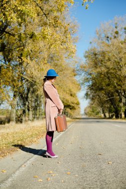lady holding retro suitcase hitchhiking