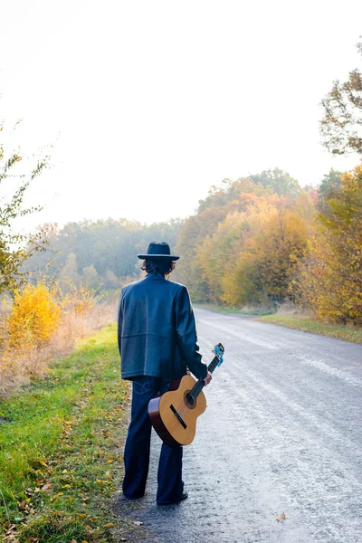 Samotny gitarzysta patrząc na pustej drodze — Zdjęcie stockowe