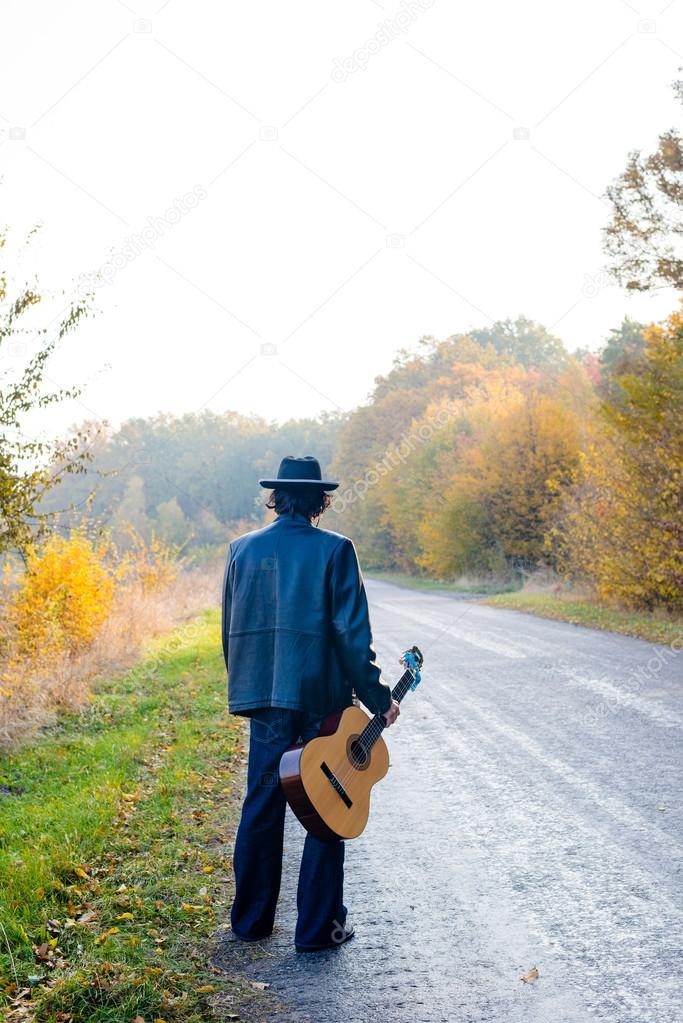Lonely guitarist looking at empty road