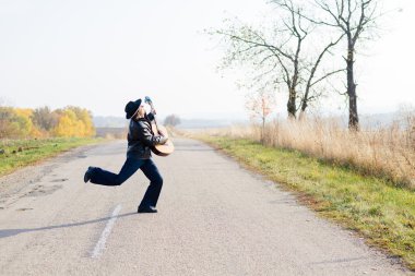 guitarist playing guitar crossing road