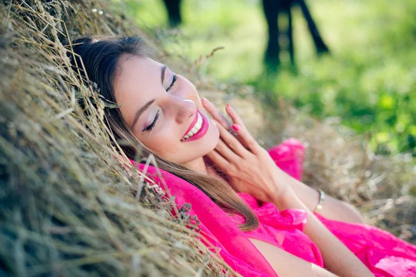 Senhora em vestido rosa relaxante no feno — Fotografia de Stock