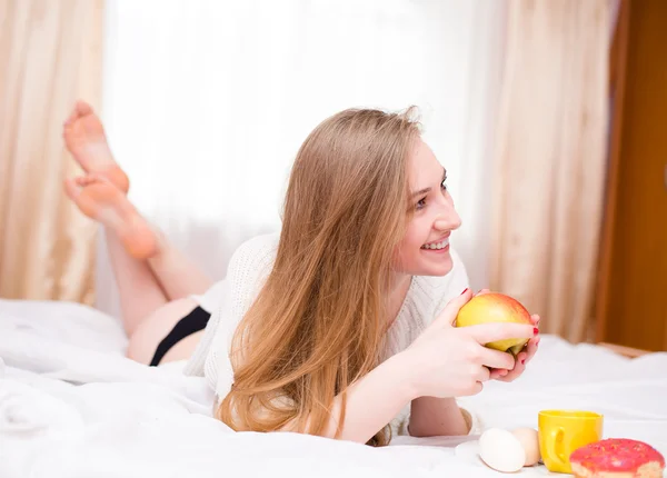 Девушка в нижнем белье ест яблоко — стоковое фото