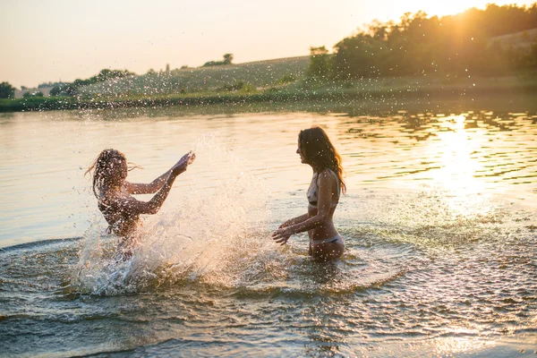 Two girls splashing in lake at sunset — 图库照片