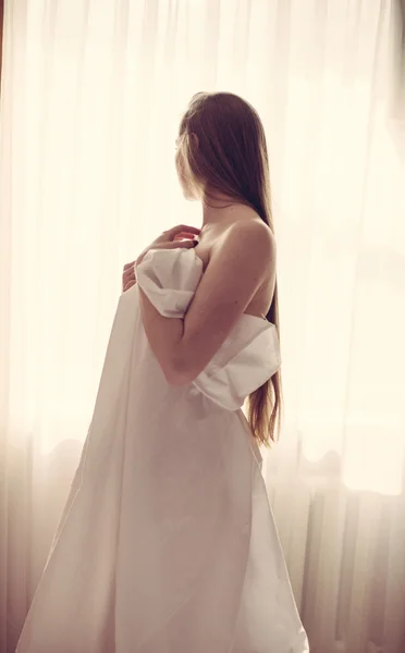 Beautiful lady wrapped in bedsheet — Stockfoto