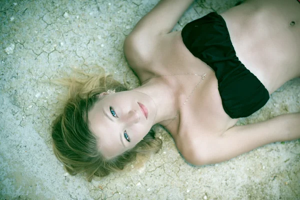 Beautiful female lying on dry ground — Zdjęcie stockowe