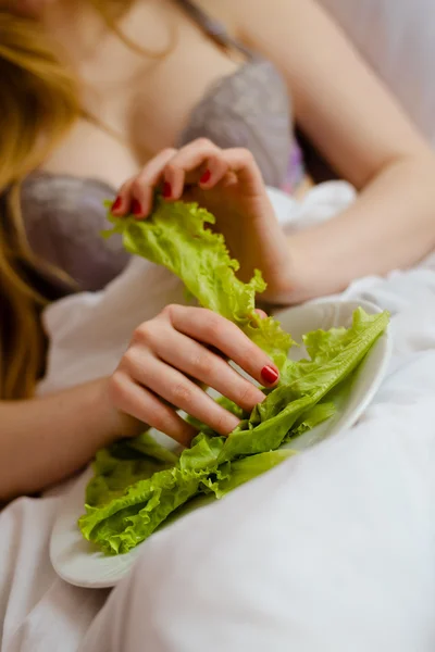 Girl in lingerie taking leaf of lettuce — Stok fotoğraf