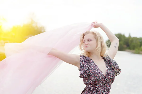 Female waving silk scarf by lake — ストック写真