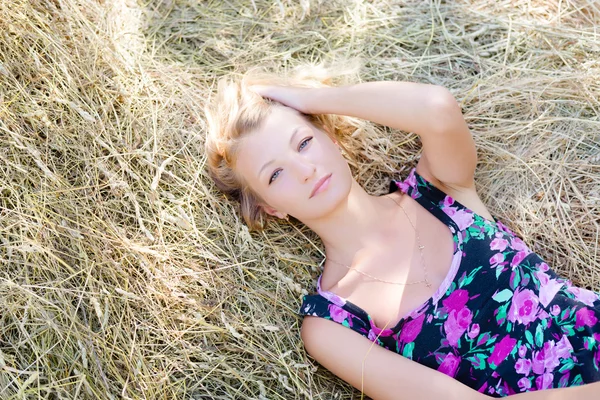 ブロンドの女の子は干し草のなかに横たわっています。 — ストック写真