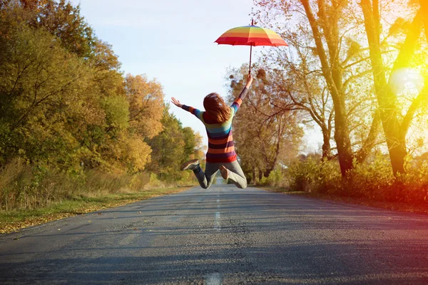 Jumping lady on empty road in autumn — Stock Photo, Image