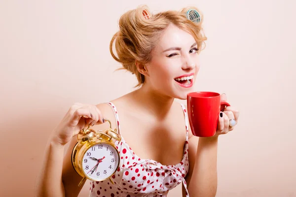 Smiling housewife with alarm-clock and cup