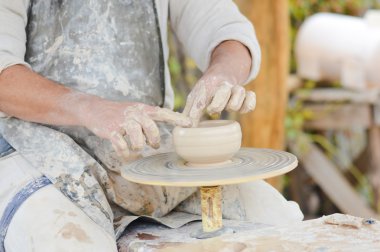 Potter hands making pot on wheel