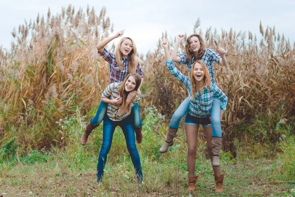 Four girlfriends playing horses in countryside — Stock Photo, Image