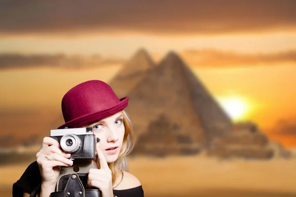 Mädchen in Brille mit Retro-Kamera auf ägyptischem Pyramidenhintergrund. — Stockfoto