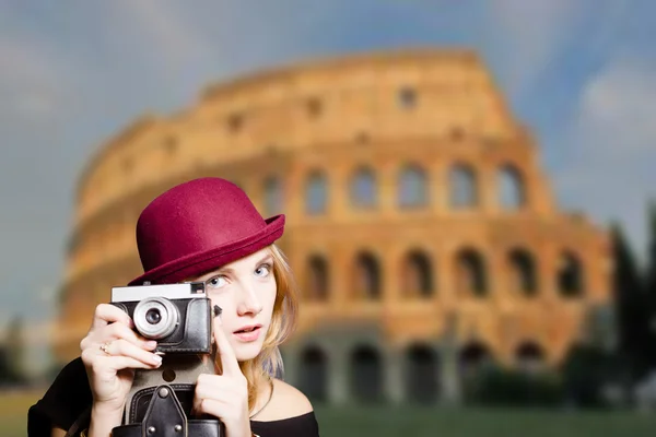 Girl in hipster glasses holding camera on Coliseum blurred background — Stock Fotó