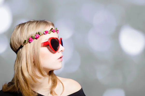 Schönes Mädchen in herzförmiger Sonnenbrille auf Bokeh-Hintergrund — Stockfoto