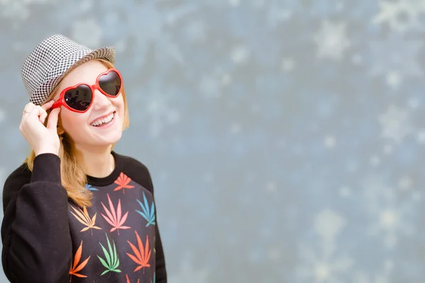 Bella donna in occhiali da sole fantasia sorridente su fiocchi di neve sfondo sfocato — Foto Stock