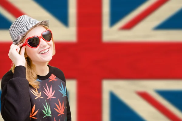 Pretty young woman in sunglasses on english union jack background — 图库照片