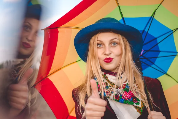 Hermosa joven con sombrero sosteniendo paraguas y soplando beso — Foto de Stock