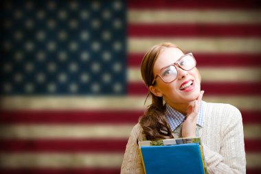Pretty student girl in glasses smiling on USA flag background