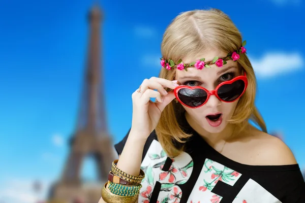 Pretty girl shocked in heart shaped sunglasses beside Eiffel tower — Stok fotoğraf