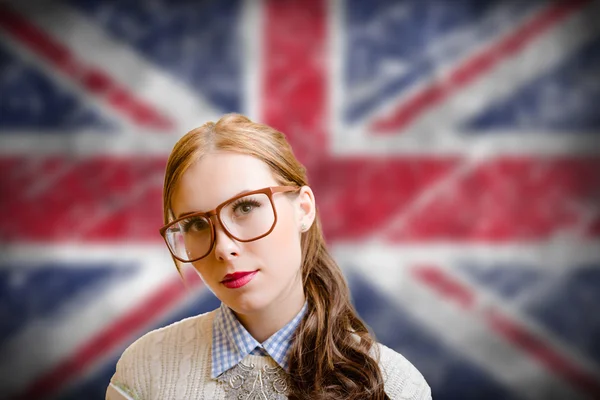 Beautiful young woman in glasses smiling on english flag background — Stock Photo, Image