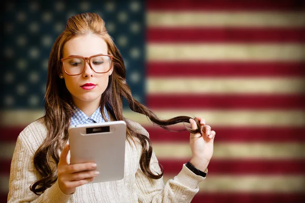 Beautiful young woman with ebook on USA flag blurred background — Φωτογραφία Αρχείου