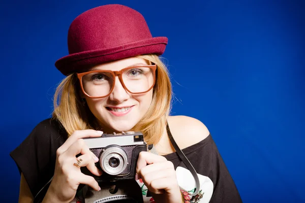 Pretty girl in big glasses and hat holding vintage camera — Zdjęcie stockowe
