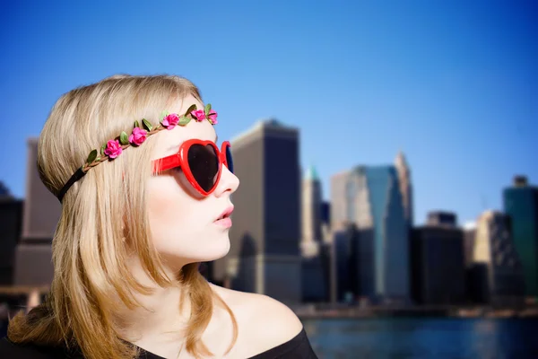 Dame blonde en lunettes de soleil et filet de fleurs sur fond de skyscapers — Photo