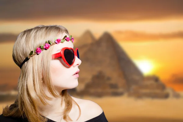 Mädchen in Brille mit Retro-Kamera auf ägyptischem Pyramidenhintergrund. — Stockfoto