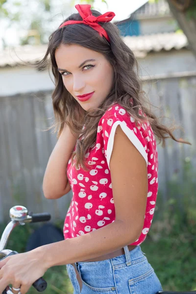 Giovane bella pinup donna in bicicletta in campagna Foto Stock