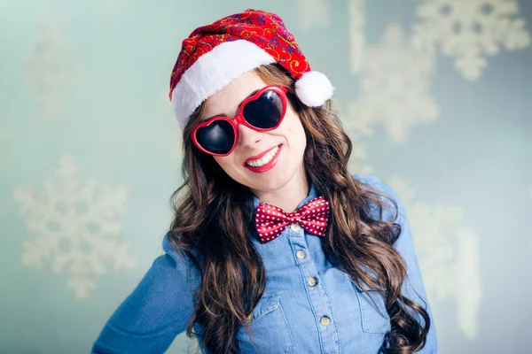 Menina hipster engraçado em forma de coração óculos de sol vestindo xmas chapéu de santa — Fotografia de Stock