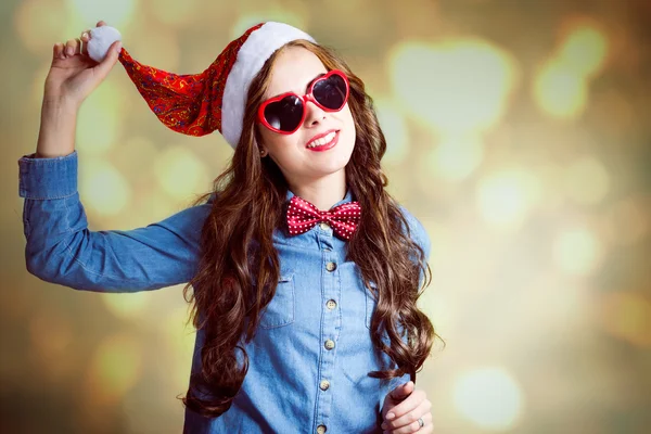 Funny hipster girl in heart shape sunglasses wearing santa hat — Stockfoto