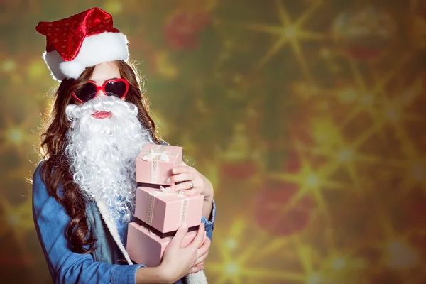 Funny girl wearing xmas santa hat and beard holding presents — 图库照片