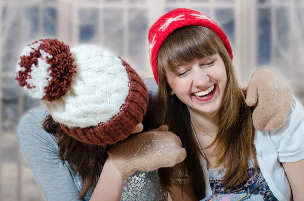 Two happy brunette girls  in winter hats and mittens hugging — Zdjęcie stockowe